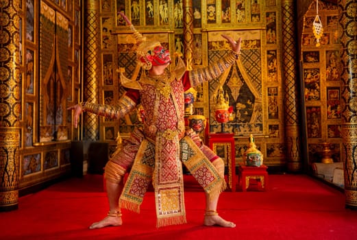 Khon or traditional Thai classic masked from the Ramakien monkey and red giant characters action of dance in front of Thai painting as background in public place.