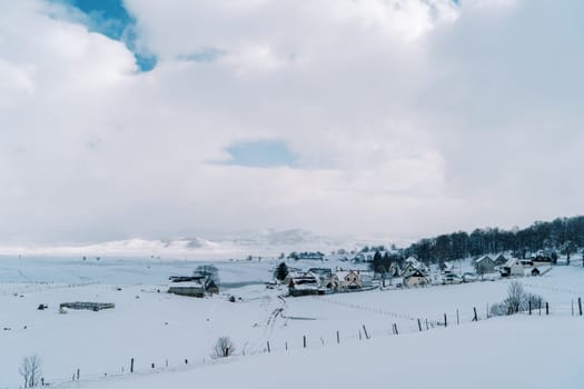 Snow-covered village at the edge of the forest in a mountain valley. High quality photo