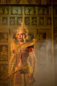 Vertical image of Portrait of Khon or traditional Thai classic masked from the Ramakien with man wear beautiful traditional dress and Thai paintings background in a public place.