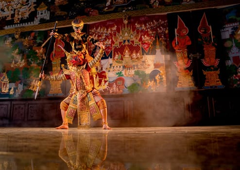 Khon or traditional Thai classic masked from the Ramakien monkey and giant characters action of fighting by spear together with black monkey and Thai painting as background in public place.