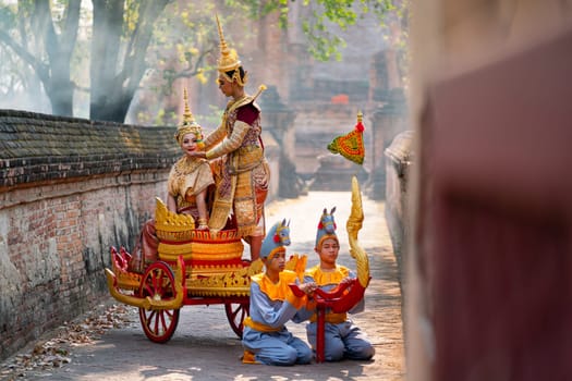 Asian man and woman with Thai old traditional dress stay together on traditional chariot in front of ancient building.