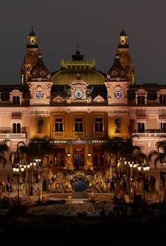 Monaco, Monte-Carlo, 12 November 2022: The famous square of Casino Monte-Carlo is at dusk, attraction night illumination, luxury cars, players, tourists, splashes of fountain. High quality photo