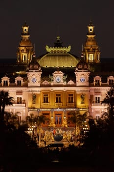 Monaco, Monte-Carlo, 12 November 2022: The famous Casino Monte-Carlo is at night, attraction night illumination, luxury cars, players, tourists, splashes of fountain. High quality photo