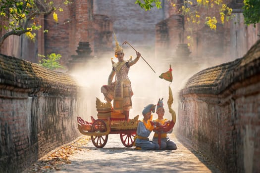 Khon or traditional Thai classic masked from the Ramakien as character of princess or king dance on traditional chariot also hold weapon stay in front of ancient building with mist or fog.