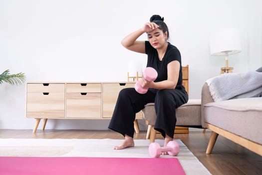 Fat woman exercising at home A beautiful oversized woman in a sports bra and casual pants sits in the living room