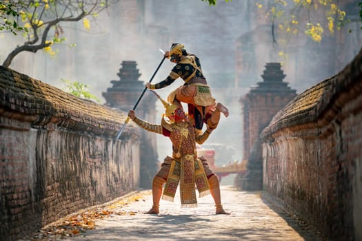 Khon or traditional Thai classic masked from the Ramakien characters action of traditional dance with fighting position and Thai ancient building in background.