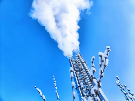 Air pollution by smoke coming out of two factory chimneys. White clouds of smoke against a blue sky background