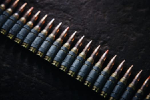 Machine gun bullet belt on the floor. Background on the military theme. Ammo, chain of ammo on concrete background. Top view of machine gun belt cartridge 7.62 mm caliber on dark blurred background.