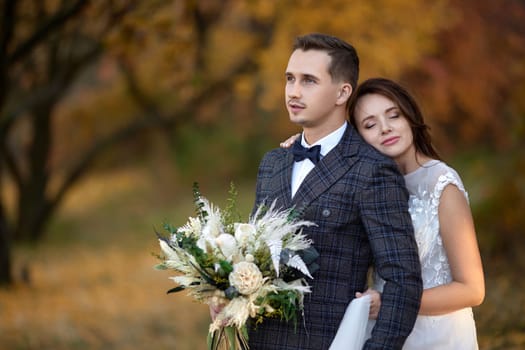 beautiful sensual bride in white wedding dress and groom hugging on their wedding on natural background