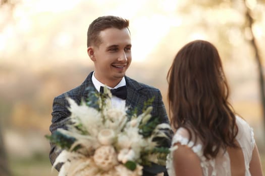 portrait of bride in white wedding dress and groom standing outdoor