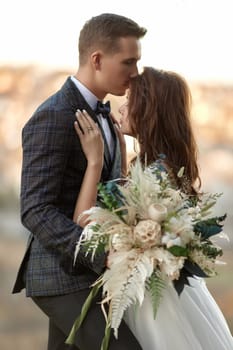 beautiful sensual bride in white wedding dress and groom standing outdoor on natural background