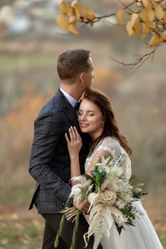 beautiful sensual bride in white wedding dress and groom standing outdoor on natural background