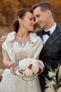 bride and groom on the nature in autumn . wedding couple with cake outdoor