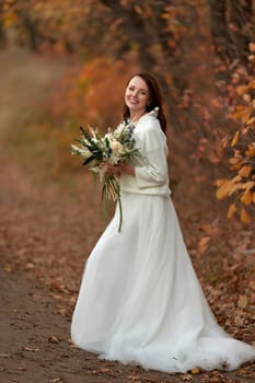 beautiful happy bride holding wedding autumn bouquet in nature