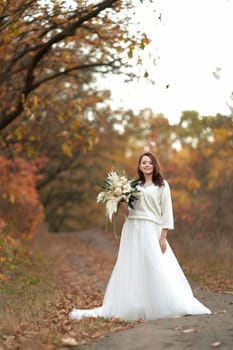 beautiful happy bride holding wedding autumn bouquet in nature