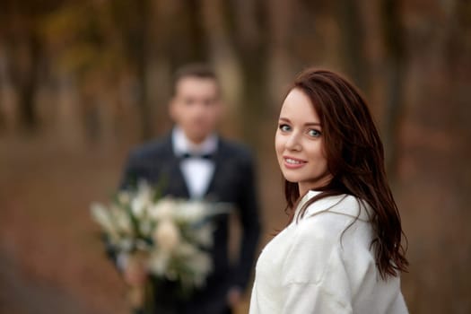 portrait of beautiful happy bride and blur groom holding wedding autumn bouquet on the background