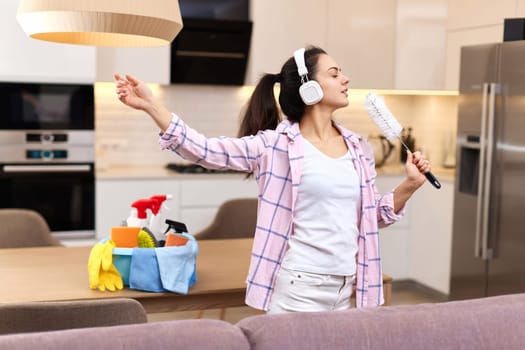 young happy housewife woman singing and cleaning her home, girl enjoying domestic work.