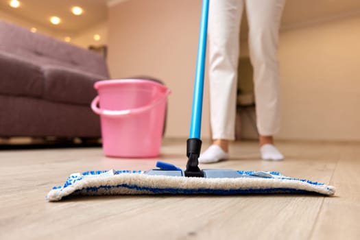 young woman cleaning floor with wet mop at home, daily housekeeping , close-up
