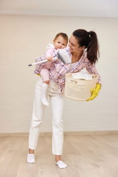 happy mother housewife is holding cute baby girl and basket with laundry , Happy family