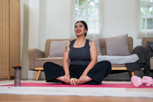 Asian overweight woman doing stretching exercise at home on fitness, Stretching training workout on yoga mat at home for good health and body shape.