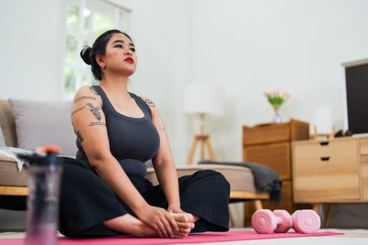 Asian overweight woman doing stretching exercise at home on fitness, Stretching training workout on yoga mat at home for good health and body shape.