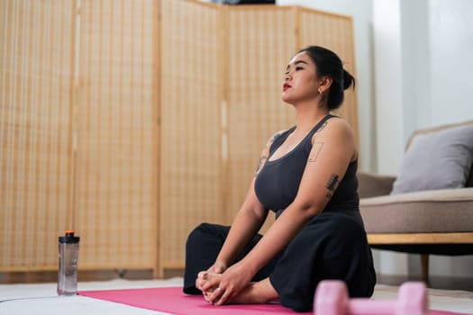 Asian overweight woman doing stretching exercise at home on fitness, Stretching training workout on yoga mat at home for good health and body shape.