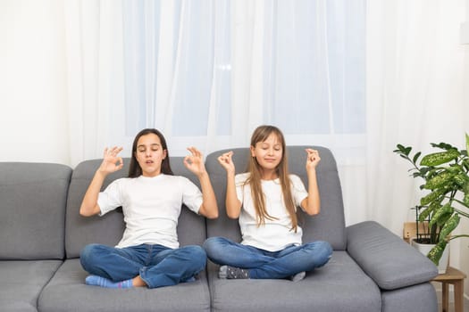 People, relationships, family, relaxation, yoga and meditation concept. girls sitting on bed, looking up, making mudra gesture, praying or meditating. High quality photo