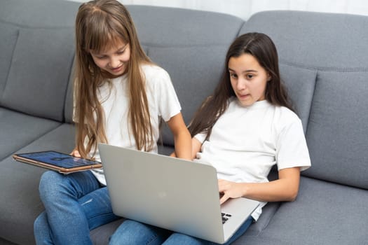 people, children, technology, friends and friendship concept - girls looking to tablet pc computers at home. High quality photo