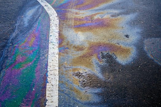 Oil, gasoline, or oil spill on wet asphalt with a parking lot and a dividing line