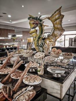 The buffet in the restaurant with a variety of dishes is decorated with the image of a dragon