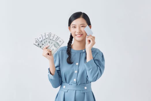 Photo of happy young woman standing isolated, holding money and credit card