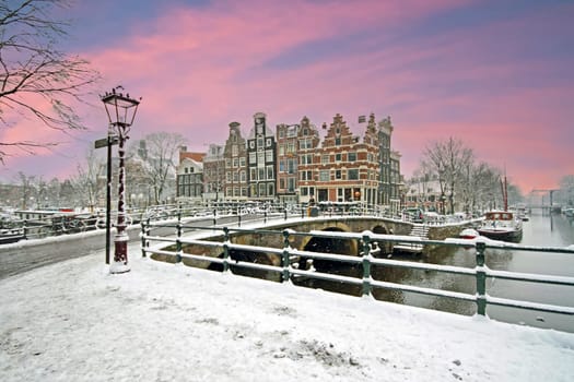 Snowy Amsterdam in the Netherlands in winter at sunset