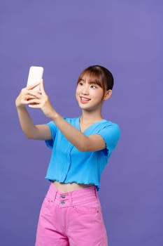 young woman taking a photo of her-self on violet background