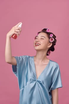 Portrait of happy asian woman with lotion spray and curlers in her hair