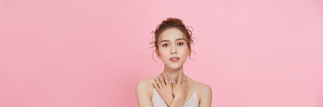  beauty Asian woman with K-beauty makeup showing fresh and clean skin isolated on pink background