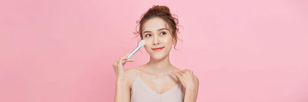 Woman applies powder on the face using makeup brush