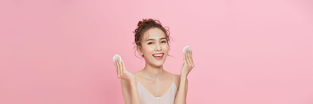 Gorgeous young asian woman holding cotton pads and smiling. Skincare and hygiene concept