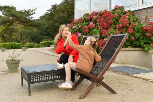 Mother and daughter spending time together in a cafe on the terrace near the hydrangea