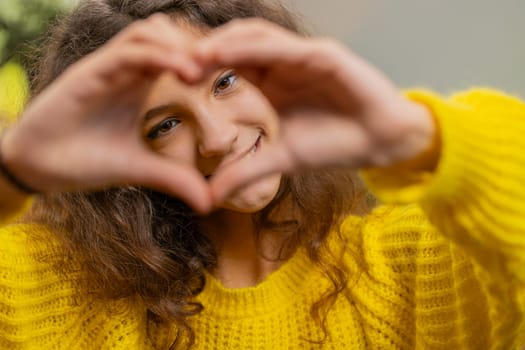 I love you. Portrait of child kid girl makes symbol of love, showing heart sign to camera express romantic feelings express sincere positive feelings. Charity, gratitude, donation. Female teen at home