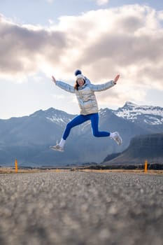 Woman jumping for joy on a lonely road in Iceland