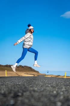 Woman jumping for joy on a lonely road in Iceland