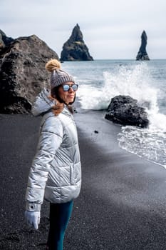 Woman with silver coat and beanie on the black beach of Reynisfjara, Iceland