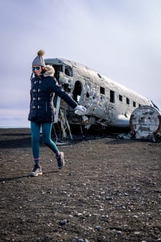 Woman walkin next to a plane wreckage in Iceland