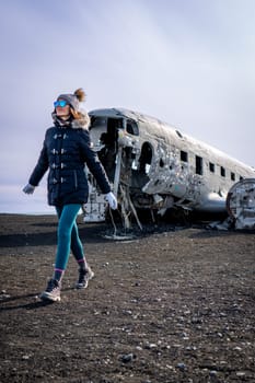 Woman walkin next to a plane wreckage in Iceland