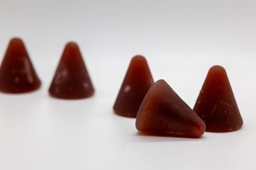 A closeup of cuberdon, a cone-shaped Belgian candy on a white background