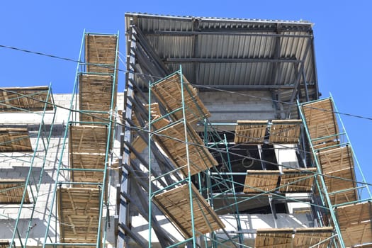 brick monolithic building under construction with wooden scaffolding