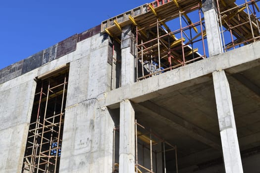 brick monolithic building under construction with wooden scaffolding