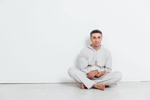 Man in pajamas sitting in a bright room against a white wall