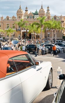 Monaco, Monte-Carlo, 29 September 2022 - Famous square Casino Monte-Carlo at sunny day, the red roof of a Rolls Royce convertible, luxury cars, wealth life, tourists take pictures of the landmark. High quality photo