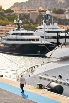 Few huge luxury yachts at the famous motorboat exhibition in the principality of Monaco, Monte Carlo, the most expensive boats for the richest people, mountain and residential complex on background. High quality photo